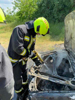 Egy nyírbátori tűzoltó a motorháztetőnél oltja a még parázsló részeket