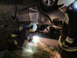 Tűzoltói beavatkozás a tetejére borult személygépkocsinál.